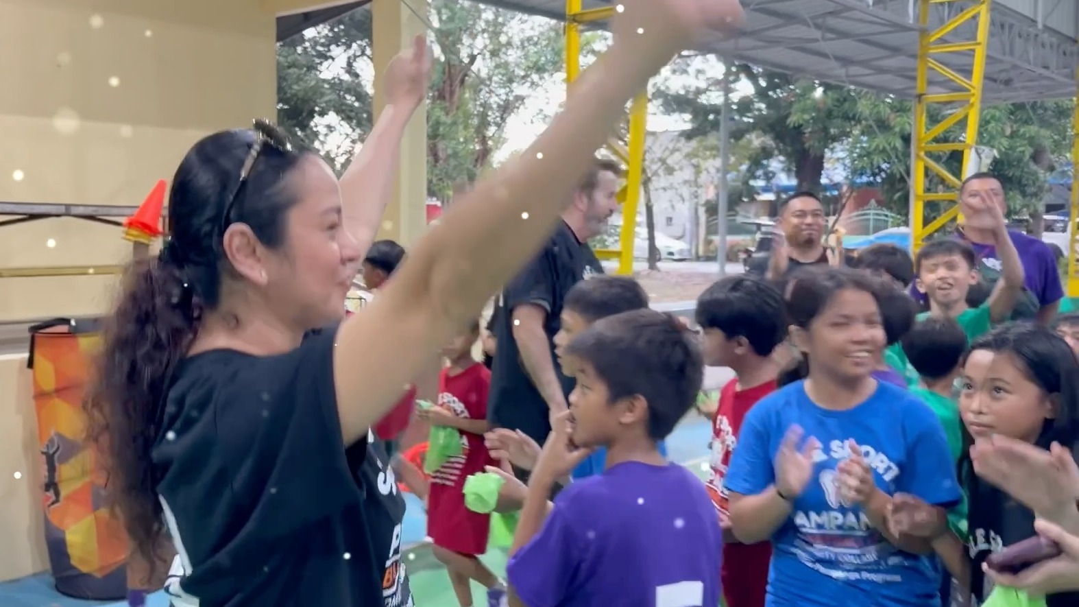 Children cheering at the end of a camp, green hygiene kit bags in their hands