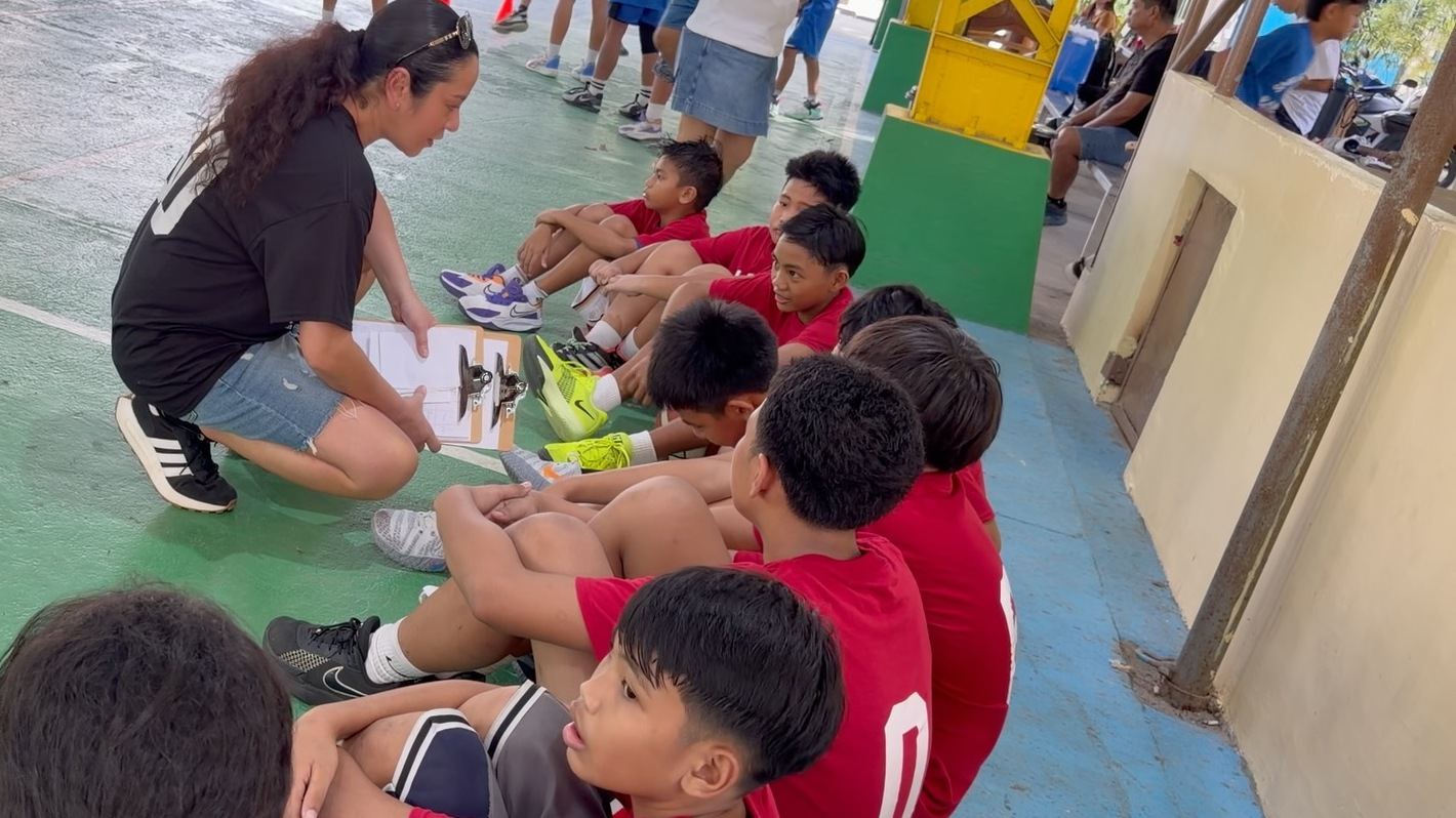 Dr. Ethel Alfaro crouched with a clipboard, teaching a seated team of children at the Smile Zone